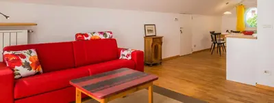 a living room with a red couch and a table at Haus Pobitzer in Caldaro