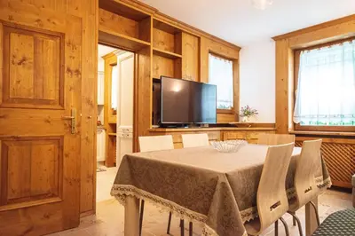 a dining room with a table and a flat screen tv at Appartamento 4 posti letto in Borca di Cadore