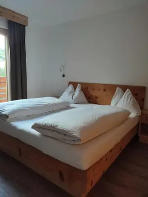 a bedroom with a wooden bed with white sheets at Apartments B&B Pretermo in Badia