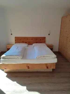 a bedroom with a wooden bed with white sheets and pillows at Apartments B&B Pretermo in Badia