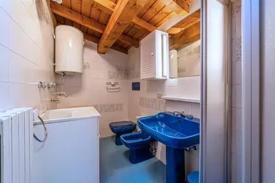 a bathroom with two toilets and a blue sink at Tizzi Home in Alleghe