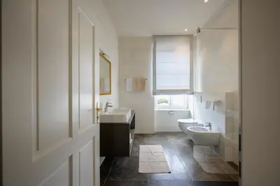 a bathroom with two sinks and a toilet and a window at Hotel Bruneck Design-Suites in Brunico