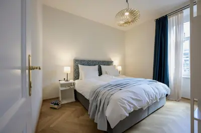 a bedroom with a bed with a blue headboard and a window at Hotel Bruneck Design-Suites in Brunico