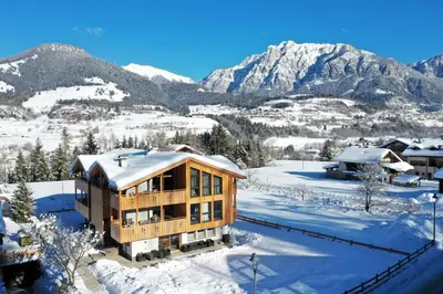 a house in the snow with mountains in the background at Mas dei Masi in Cavalese