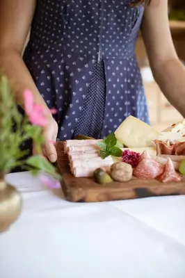 a woman is standing next to a plate of food at Nössinghof in Tirolo