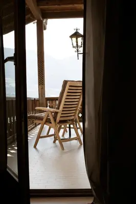 a rocking chair on the balcony of a house at Nössinghof in Tirolo