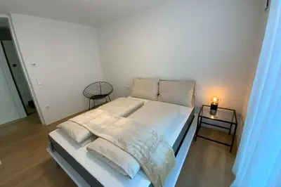 a white bed with pillows and a night stand in a bedroom at Riversuite in Bressanone