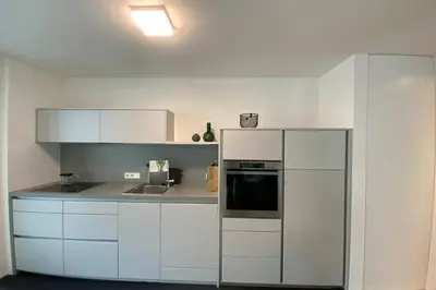 a kitchen with white cabinets and a refrigerator at Riversuite in Bressanone