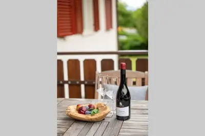 a bottle of wine and a bowl of fruit on a table at Ferienwohnung am Kalterer See in Südtirol in Caldaro