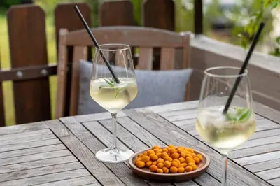 two glasses of wine and a plate of food on a wooden table at Ferienwohnung am Kalterer See in Südtirol in Caldaro