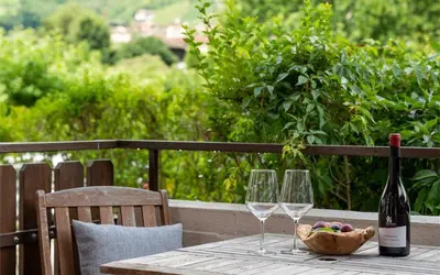 a table with two wine glasses and a basket of grapes at Ferienwohnung am Kalterer See in Südtirol in Caldaro
