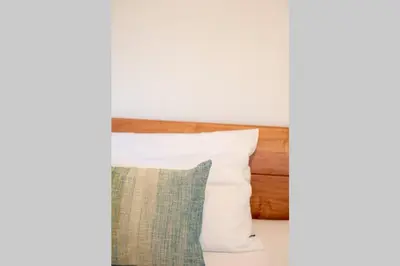 a bed with white pillows and a wooden headboard at Ferienwohnung am Kalterer See in Südtirol in Caldaro