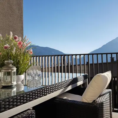 a table and chairs on a balcony with a glass table at Rooftop-Schenna in Schenna