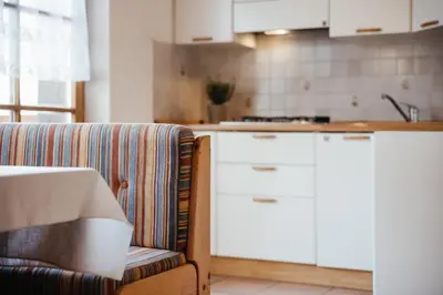 a kitchen with white cabinets and a couch at Apartments Roda de Ciar in Badia