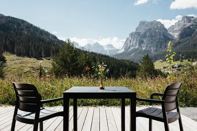 a table and two chairs on a deck with a view of mountains at Apartments Roda de Ciar in Badia