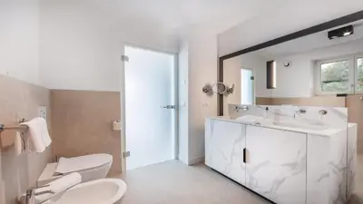 a white bathroom with two sinks and a mirror at Palm Loggias Meran in Merano