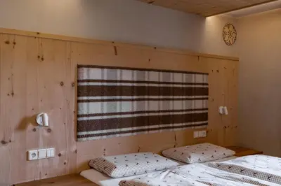 two beds in a room with wooden walls and a window at Ciasa Iachin - Dolomites Dream Retreat in San Martino in Badia