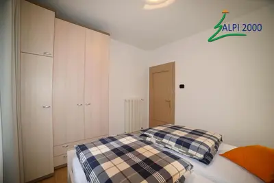 a bedroom with a bed with a plaid blanket at Casa Dolomiti - BERTA in Campitello di Fassa