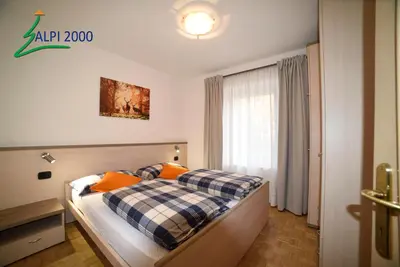 a bedroom with a bed with orange pillows and a window at Casa Dolomiti - BERTA in Campitello di Fassa