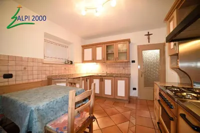 a kitchen with a table and a cross on the wall at Casa Dolomiti - BERTA in Campitello di Fassa
