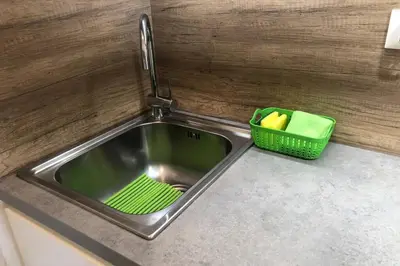 a kitchen sink with a green basket next to it at Brunico 19 in Brunico