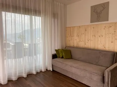 a living room with a couch and a large window at Alpine Chalet Aurora Dolomites in Laion