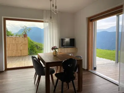 a dining room with a table and chairs and a large window at Alpine Chalet Aurora Dolomites in Laion