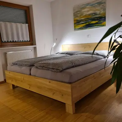 a wooden bed in a bedroom with a plant at Sarah's nest - your mountain resort in Villa Ottone