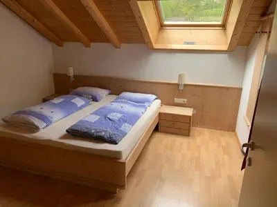 a bedroom with a bed with blue pillows and a window at Santlhof - Sauvignon in Cortaccia