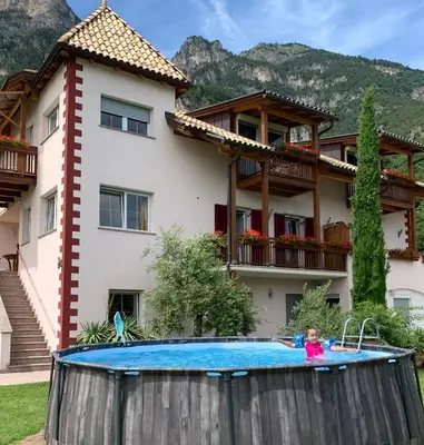 a little girl playing in a swimming pool in front of a house at Santlhof - Sauvignon in Cortaccia