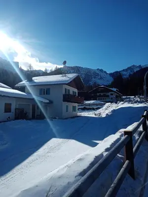 a snow covered yard with a house and a fence at Relax al lago di Braies in Braies