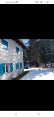 a white building with blue windows and a snowy street at Relax al lago di Braies in Braies