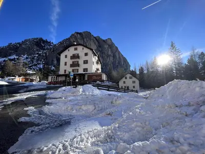 a large building in front of a mountain with snow at Hotel Al Sasso di Stria in Andraz