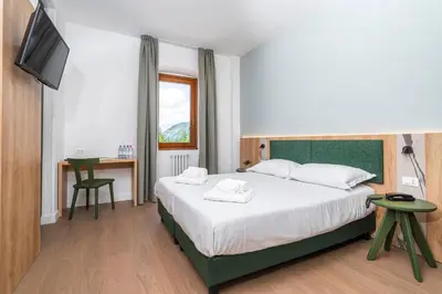 a bedroom with a bed and a desk and a television at Hotel Al Sasso di Stria in Andraz