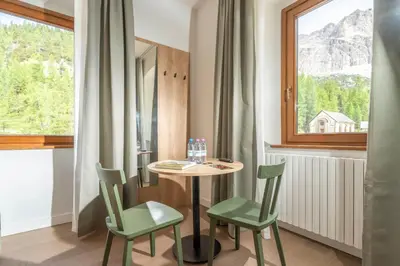 a small table and chairs in a room with a window at Hotel Al Sasso di Stria in Andraz