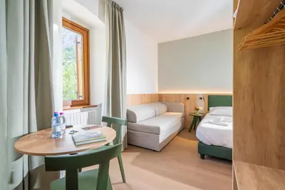 a hotel room with a table and a bed and a room at Hotel Al Sasso di Stria in Andraz