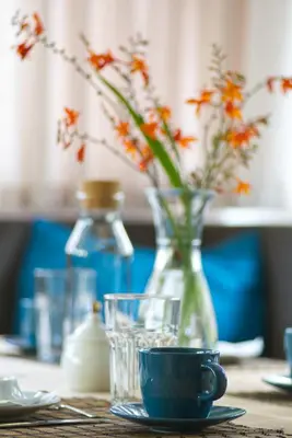 a table with a vase of flowers and a cup at CityChalet family Bozen in Bolzano