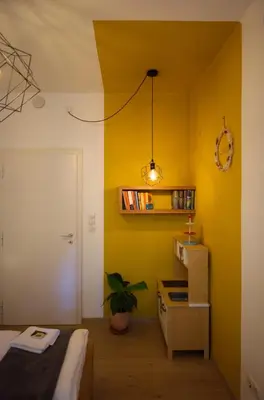 a room with a yellow wall and a table with a plant at CityChalet family Bozen in Bolzano