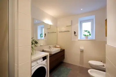 a bathroom with a sink and a washing machine at CityChalet family Bozen in Bolzano