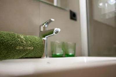 a bathroom sink with a green towel and two glasses at Veraltenhof Agriturismo B&B in Tires