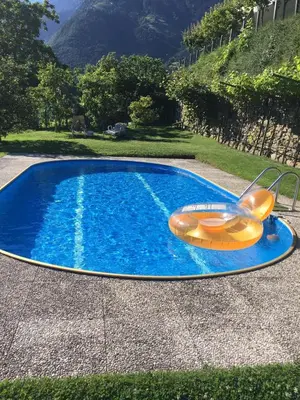 a swimming pool with a raft and a chair in it at Villa Corazza-Bezauberndes Appartment+ Schwimmbad in Tirolo