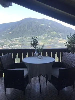 a table with chairs and a vase with flowers on it at Villa Corazza-Bezauberndes Appartment+ Schwimmbad in Tirolo