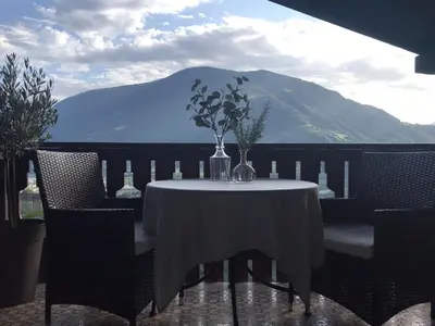a table with a vase of flowers on a balcony at Villa Corazza-Bezauberndes Appartment+ Schwimmbad in Tirolo