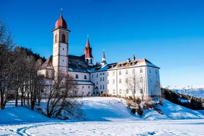 a castle in the snow with snow covered ground at Hotel Leonhard in Nova Ponente