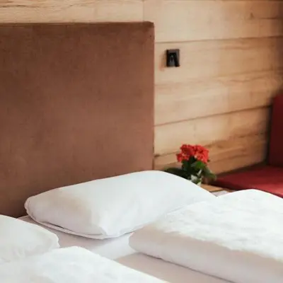 two white beds in a room with a vase of flowers at Hotel Leonhard in Nova Ponente