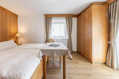 a bedroom with a bed and a table and a window at Villa Resi B&B in Corvara in Badia