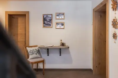 a room with a table on the wall with a chair at Villa Resi B&B in Corvara in Badia