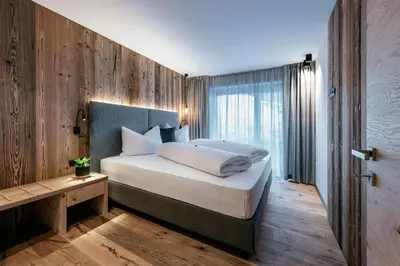 a bedroom with a large bed with a wooden wall at Guesthouse Plose in Bressanone
