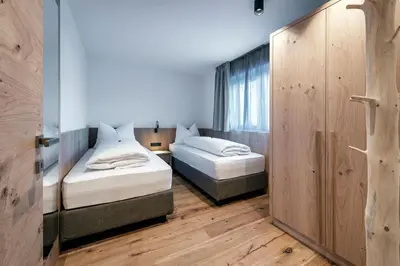 two beds in a room with wooden floors at Guesthouse Plose in Bressanone