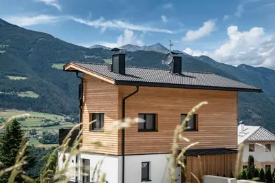 a wooden house with mountains in the background at Guesthouse Plose in Bressanone